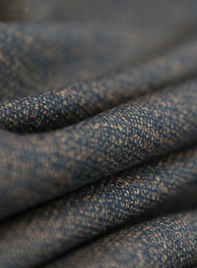 Close-up of draped blue woven wool fabric with orange and beige flecks, soft folds in shallow focus
