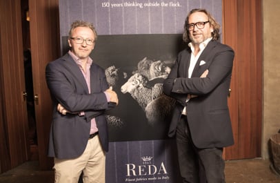 Two men with crossed arms pose beside a Reda banner showing sheep, with the text "150 years thinking outside the flock".