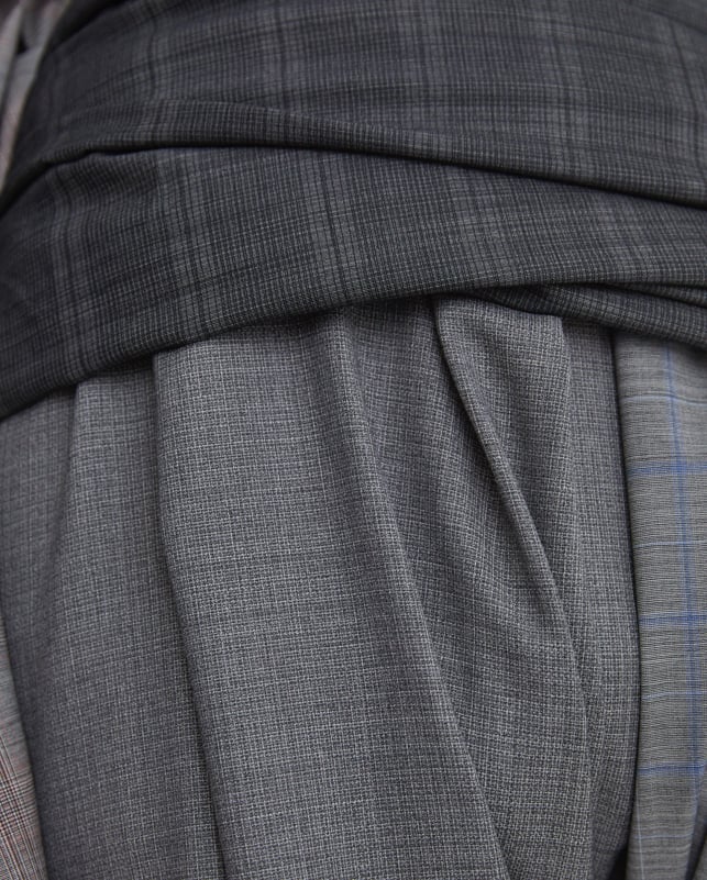 Close-up of draped grey wool fabrics in different checks and textures, with a blue check detail on the right