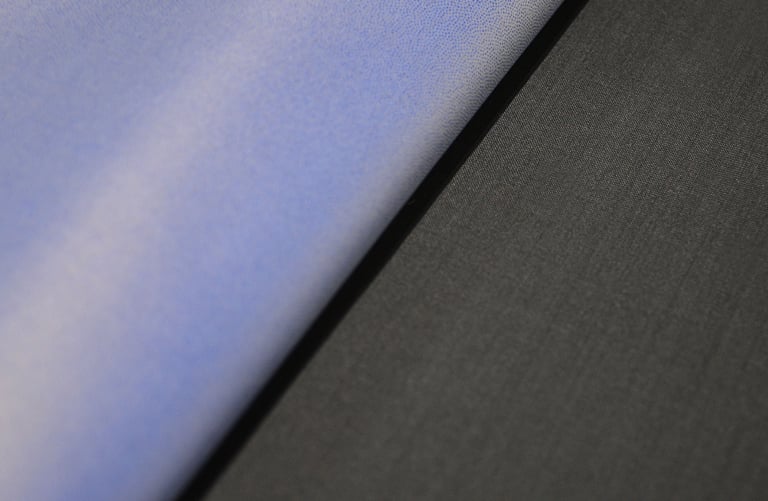 Primo piano di un tessuto azzurro piegato in diagonale su un panno grigio scuro in lana tessuta