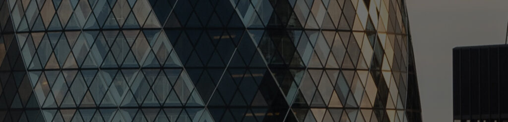 Close-up of a curved glass skyscraper facade with a diamond-shaped lattice, dimly lit against a grey sky