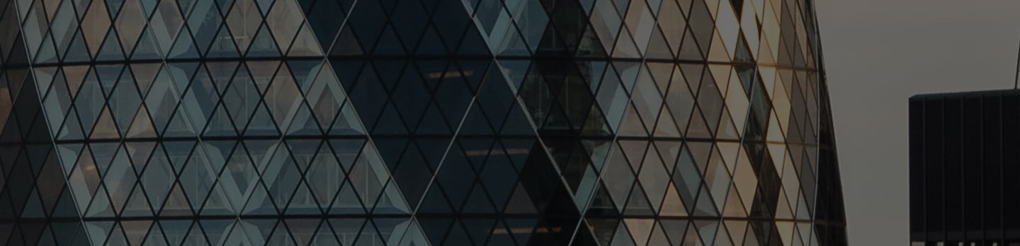 Close-up of a curved glass skyscraper facade with a diamond-shaped lattice, dimly lit against a grey sky