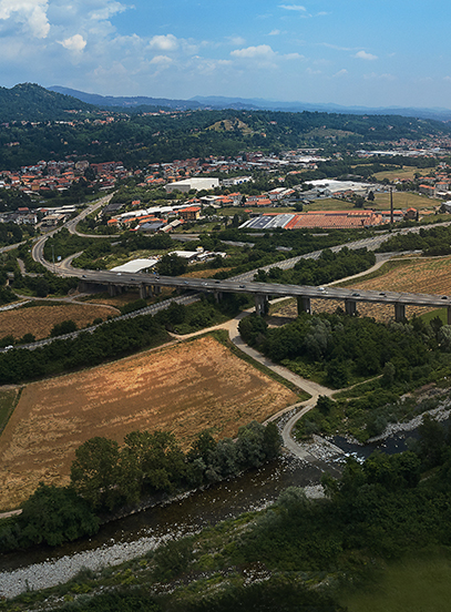 Aerial view of a river valley with a highway viaduct, fields, buildings and wooded hills beyond
