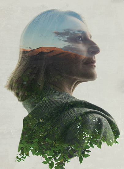 Double exposure profile of a woman in a plaid wool jacket, with sky, mountains and leaves inside her silhouette