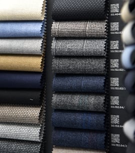 Stacked wool fabric swatches in blue, grey, beige and black, with QR code labels on the right