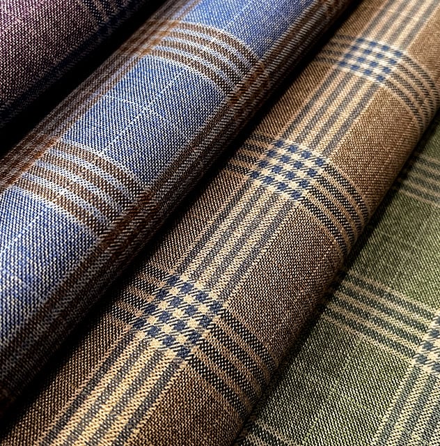 Rolls of checked woolen fabric in blue, brown and green, with overlapping plaid patterns
