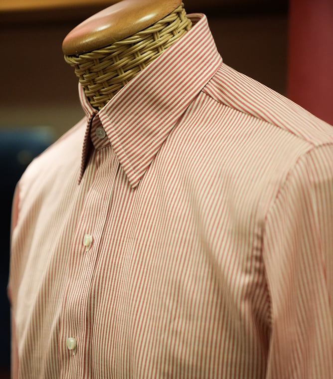 Red and white striped button-up shirt with a pointed collar on a mannequin with a wicker neck