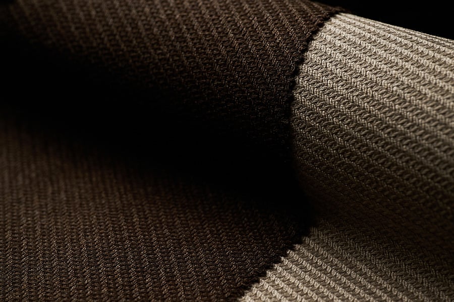 Close-up of a dark brown textured woolen fabric with a fine ribbed weave, folded to show a lighter side
