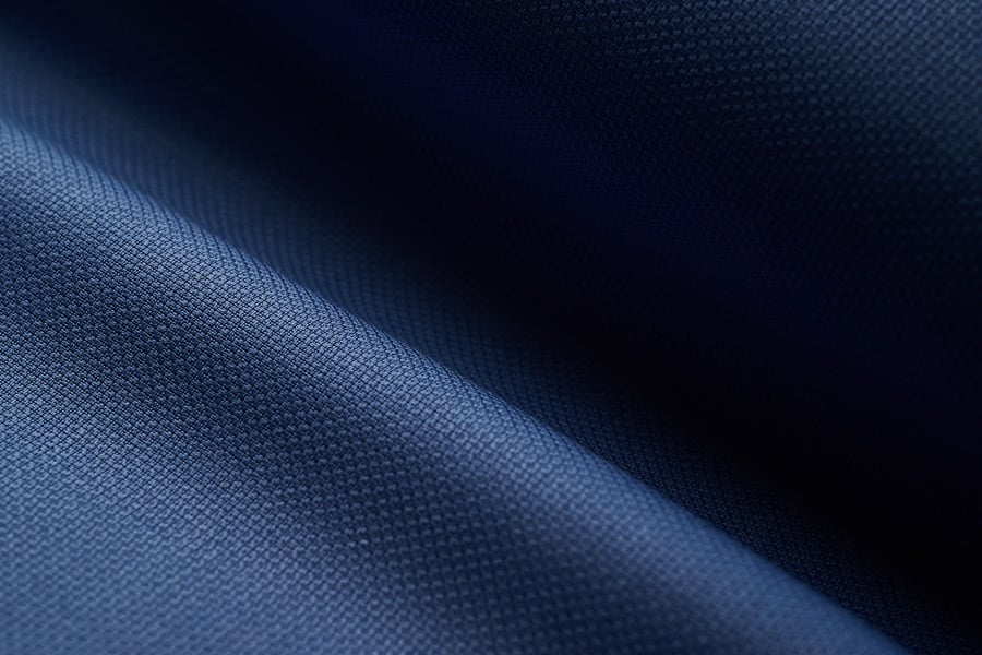 Close-up of navy blue woven fabric with fine texture, softly folded and lit from the left