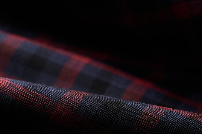 Close-up of folded red and navy checked woven fabric against a dark background