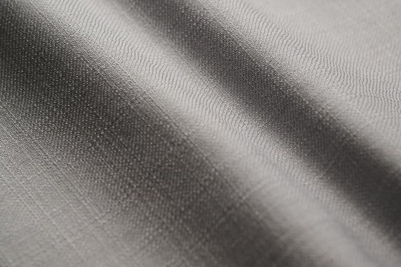 Close-up of a light grey woven wool fabric with soft folds and fine, visible texture