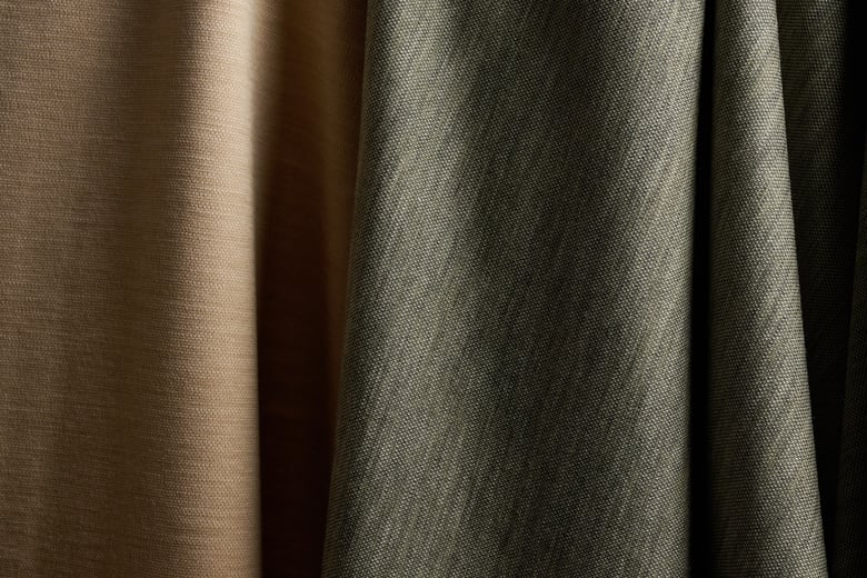 Close-up of two draped fabrics, one beige and one olive green with a fine woven texture
