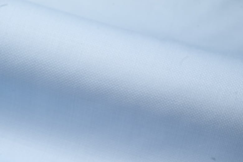 Close-up of light blue fabric with a fine woven texture, draped in soft folds