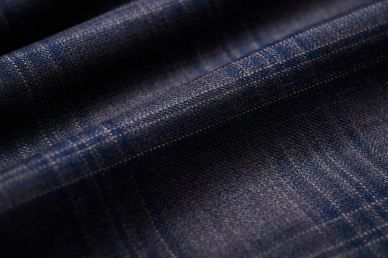 Close-up of navy wool fabric with a subtle blue and grey check pattern, softly folded