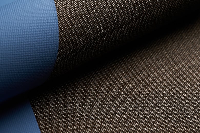 Close-up of a dark brown woven wool fabric draped over a blue fabric, showing the texture of the weave