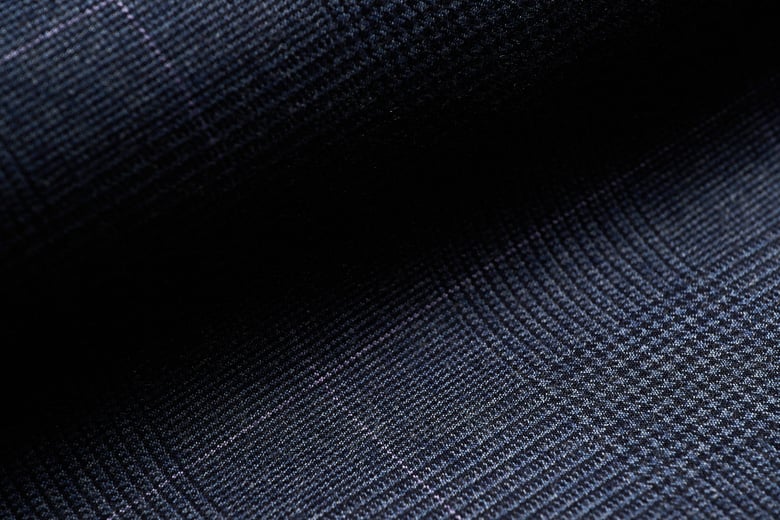 Close-up of navy blue wool flannel fabric with a subtle glen plaid check and thin light overcheck