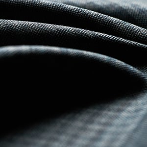 Close-up of dark charcoal woven fabric with a fine textured weave, draped in soft folds