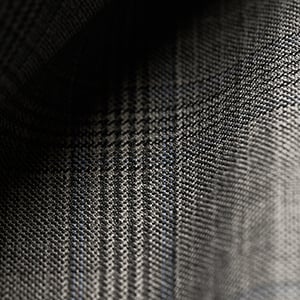 Close-up of grey wool fabric with a subtle glen check pattern and soft folds