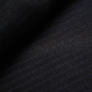 Close-up of dark charcoal wool fabric with a subtle herringbone weave and fine vertical stripes