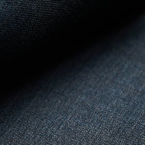 Close-up of dark navy blue woolen fabric with a fine twill weave, fading into shadow