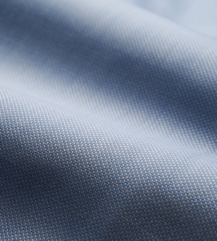 Close-up of light blue woven wool fabric with a fine textured weave, softly draped in gentle folds