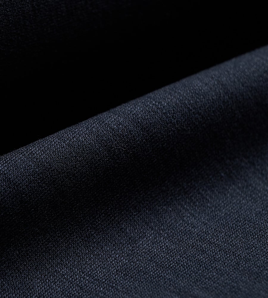 Close-up of a navy blue woven wool fabric folded over a darker background, showing its fine texture