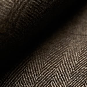 Close-up of dark brown herringbone wool fabric with soft folds and shadowed light