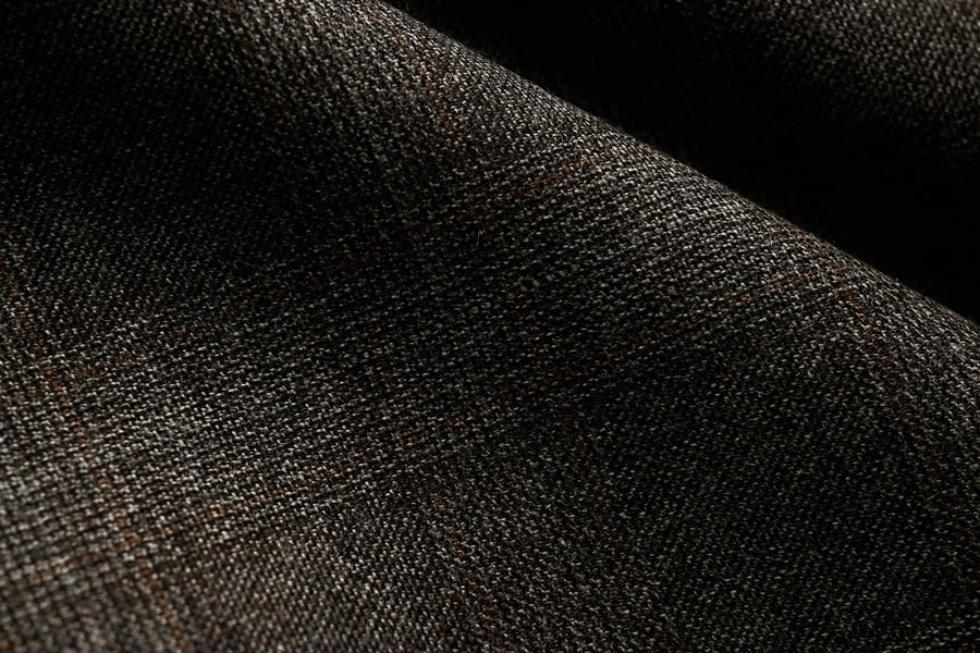 Close-up of dark brown woven wool fabric with a subtle orange windowpane check, in soft folds