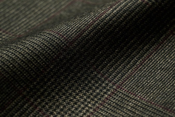 Close-up of dark grey-green wool flannel with a subtle glen check and thin burgundy overcheck, in soft folds