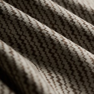 Draped woolen fabric with a brown and cream zigzag chevron weave, folded in soft waves