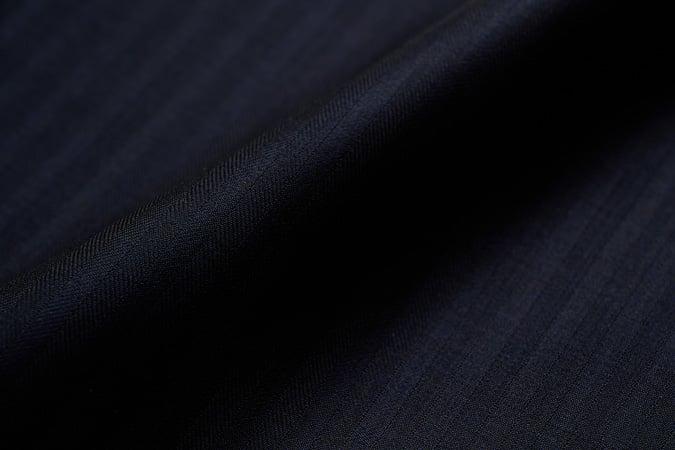 Close-up of dark navy wool fabric with subtle tonal stripes and soft folds