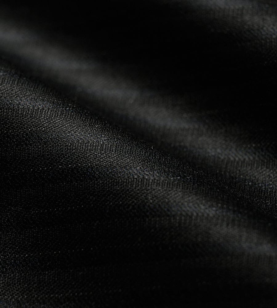 Close-up of black wool fabric with soft folds and a fine woven texture in dramatic low light