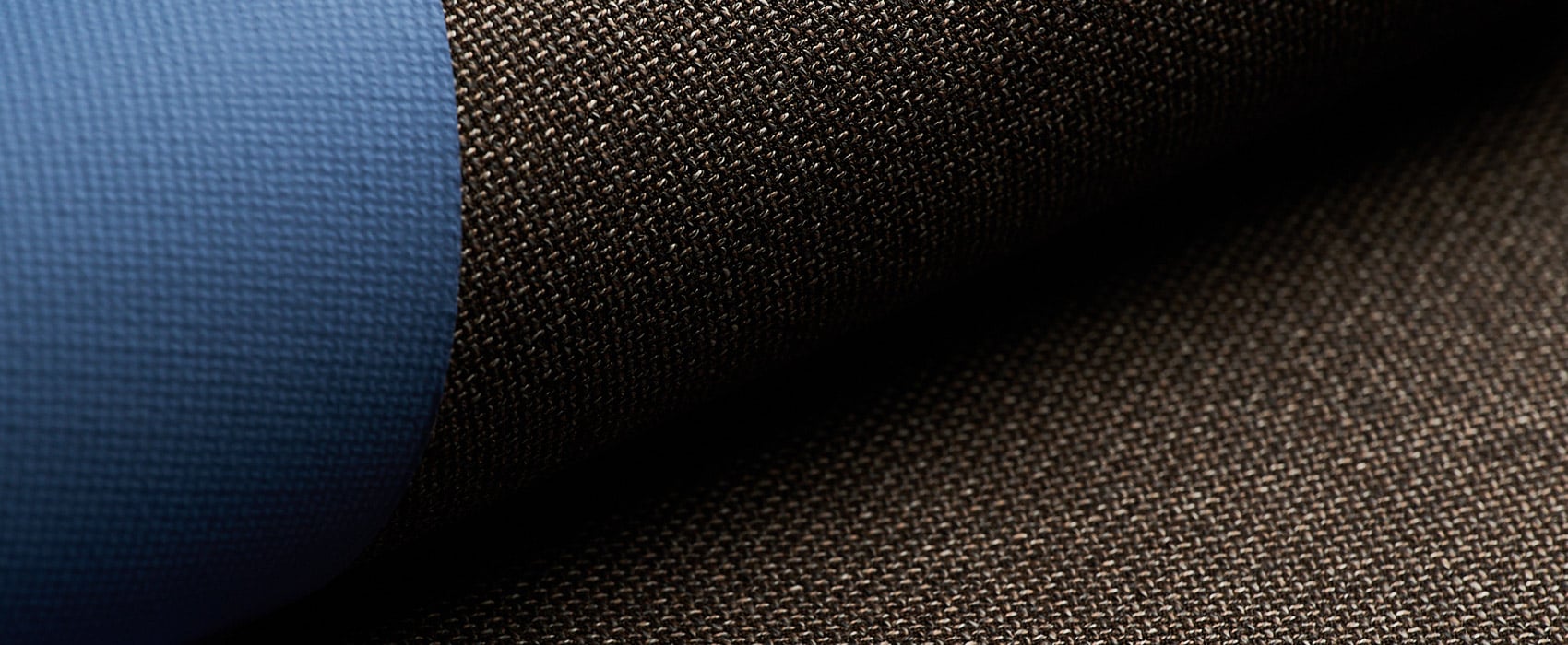 Close-up of dark brown woven wool fabric folded over a smooth blue textured material