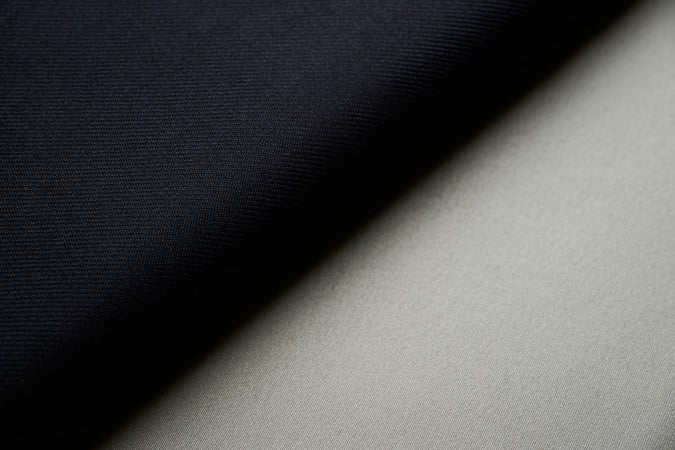 Close-up of two fabric swatches, dark navy and light grey, overlapping along a diagonal line