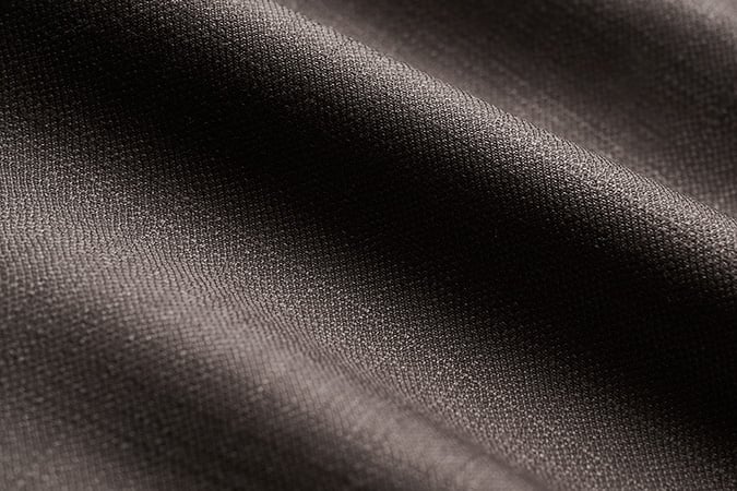 Close-up of dark taupe-brown woven wool fabric with soft folds and a fine, textured weave