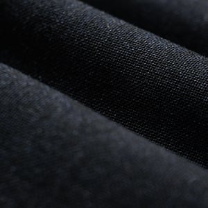 Close-up of dark navy woven fabric folded in soft waves, showing the fine texture of the weave
