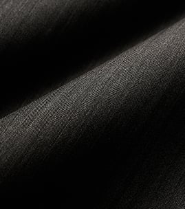 Close-up of dark charcoal wool fabric with soft folds and a fine diagonal weave texture