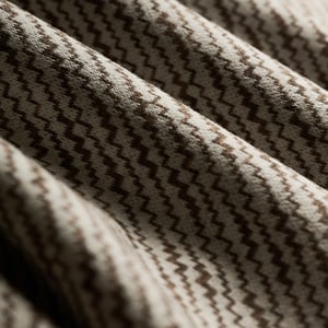 Close-up of draped fabric with a brown and cream zigzag chevron weave in soft folds