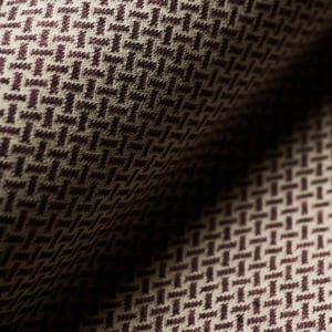Close-up of draped wool fabric with a dark burgundy and beige woven geometric micro-pattern