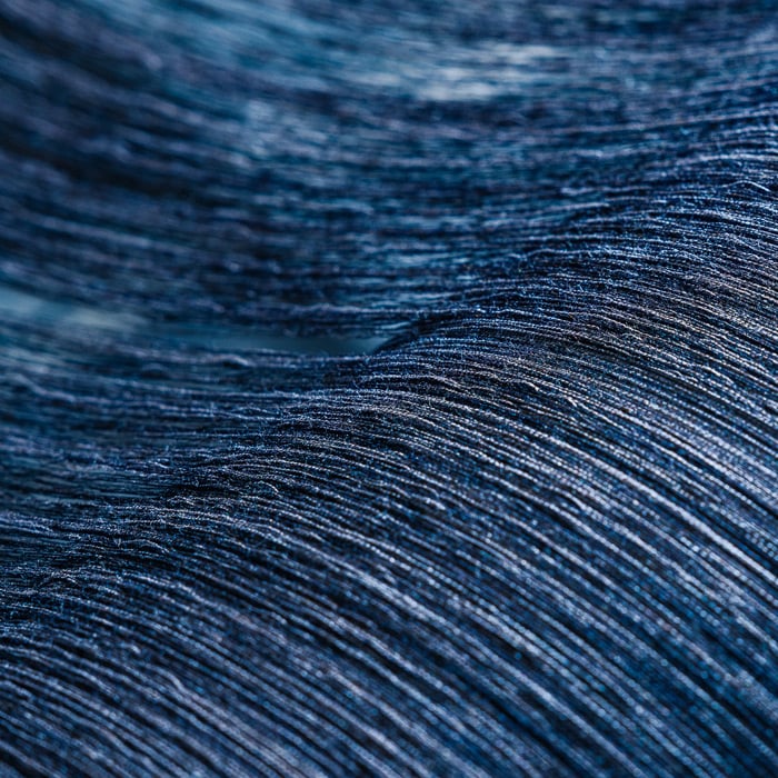Close-up of a deep blue woven fabric with fine horizontal threads forming soft, undulating folds