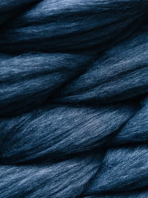 Close-up of thick twisted strands of soft navy blue wool roving