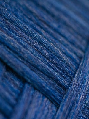 Close-up of navy blue woolen yarn strands with a soft, fuzzy texture, wound in overlapping layers