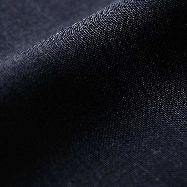 Close-up of dark navy woolen fabric with a fine woven texture and soft folds