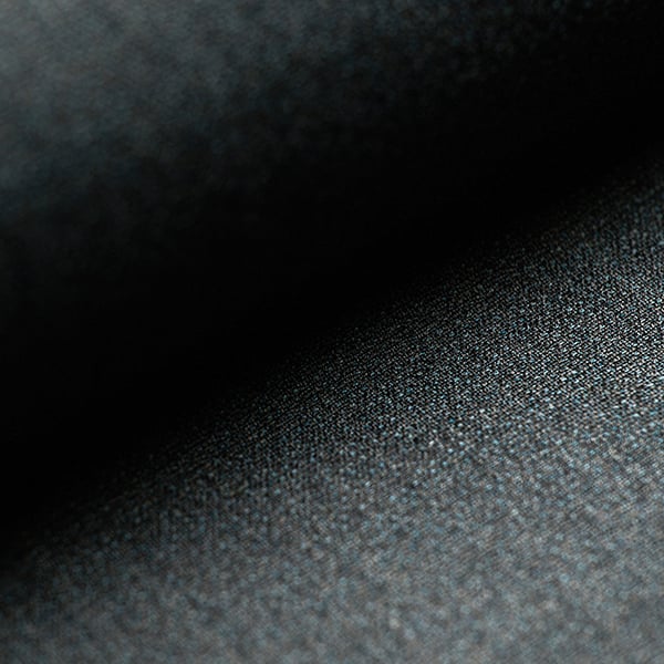 Close-up of dark grey woven wool fabric with fine texture, fading into deep shadow