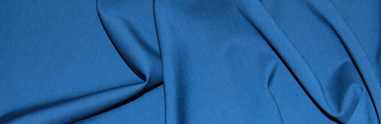 Close-up of blue wool fabric with soft folds and draped creases