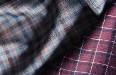 Two folded wool fabrics: a gray, blue and pink plaid and a burgundy check with thin light lines