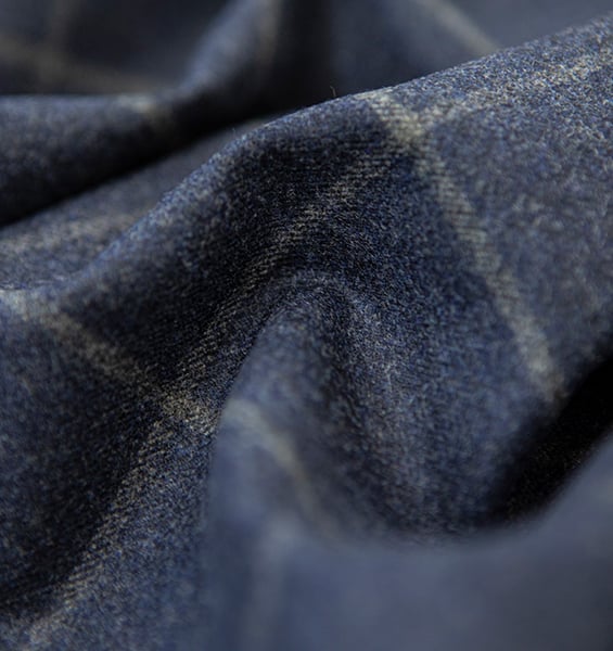 Close-up of draped navy blue wool fabric with a subtle beige windowpane check pattern