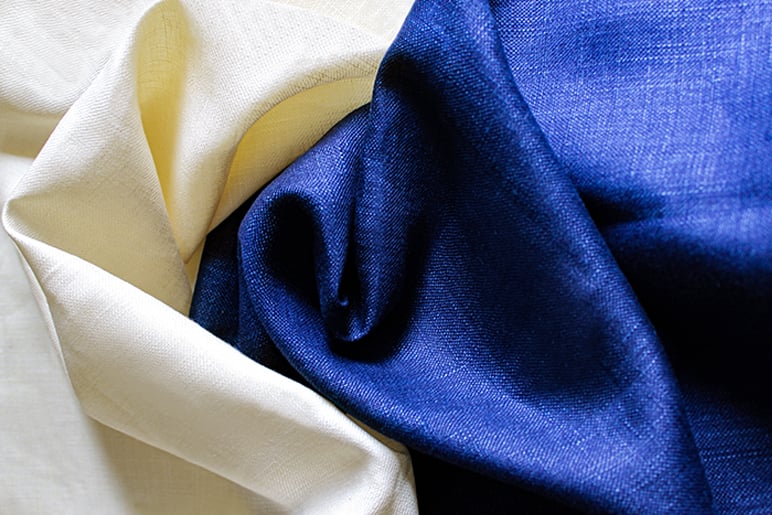 Draped cream and navy blue woven fabrics with visible texture, folded side by side