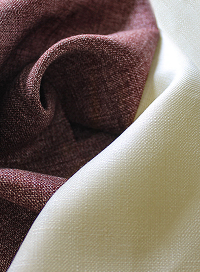Close-up of draped woven fabrics in deep burgundy and cream, showing their textured weave