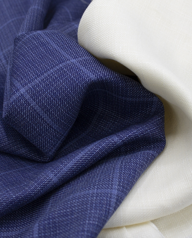 Blue windowpane-check woven fabric draped in folds beside a piece of cream-colored fabric